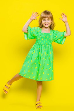 Genç sarışın çocuk, müzik dinleyen, disko dinleyen, eğlenen, el kol hareketi yapan, partide rahatlayan. Sarı arka planda izole edilmiş küçük çocuklar. Dikey