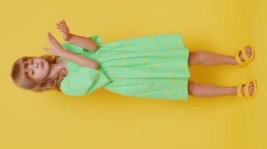 Boşa harcayan, etrafa para saçan çocuk, daha fazla bahşiş, büyük kar, piyango ikramiyesi, başarılı alışveriş ödemesi, nakit para. Sarı arka planda küçük çocuklar. Dikey