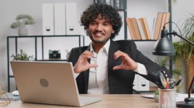 I love you. Indian business man makes symbol of love, showing heart sign to camera, express romantic feelings, express sincere positive feelings at home office workplace. Charity, gratitude, donation