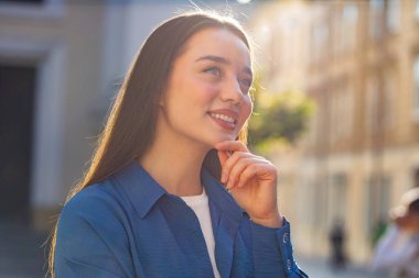 Mutlu genç kadın yüzü gülümsemesi, kameraya bakan mutlu yüz ifadesi hayal kurma, dinlenme, rahatlama tatmin edici haberler. Güneşli bir şehirde akıllı telefon tutan güzel bir kız.