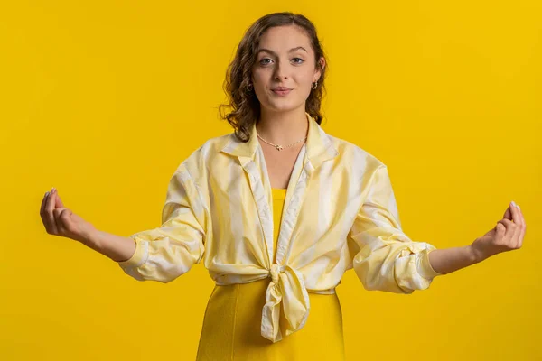 Keep calm down, relax, inner balance. Young woman breathes deeply with mudra gesture, eyes closed, meditating with concentrated thoughts, peaceful mind. Attractive girl isolated on yellow background
