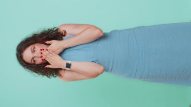 Hiçbir şey söylemeyeceğim. Korkmuş kadın ağzını kapatıyor, kameraya korkmuş bakıyor, hayır işareti yapıyor, korkunç sırrı, inanılmaz gerçeği söylemeyi reddediyor. Mavi arka plandaki kız. Dikey