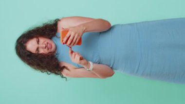 Bir kadın cep telefonu akıllı telefon daktilosu kullanıyor. Ani piyango sonuçlarını kaybediyor. Kötü talih, kayıp, başarısızlık. Güzel esmer kız mavi stüdyo arka planında tek başına. Dikey