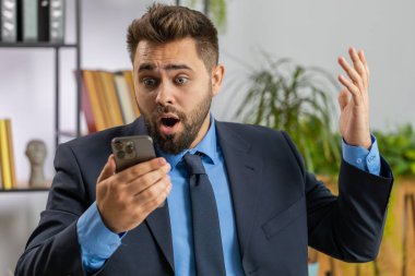 Aman Tanrım, vay canına. Akıllı telefon üzerinde çalışan mutlu, genç, beyaz iş adamı ani zafer, maç kazanma, piyango hedefi başarısı ve iyi haberler karşısında şoka uğradı. Sakallı menajer ofisteki serbest çalışan adam.