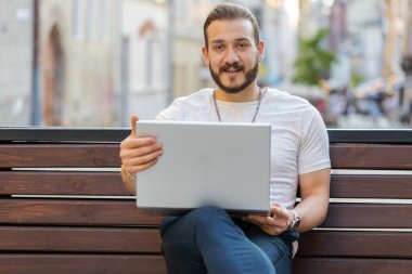 Serbest çalışan bir adamın portresi açık şehir sokaklarındaki bankta otururken dizüstü bilgisayarı açıyor. Ortadoğulu adam defter üzerinde çalışıyor, mesajlar gönderiyor, online alışverişler yapıyor, film izliyor. Kasaba yaşam tarzları