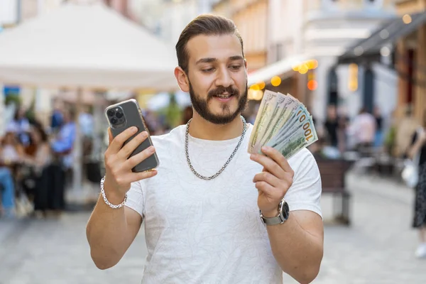 Glade Rige Unge Mand Tælle Penge Dollar Kontanter Bruge Smartphone - Stock-foto