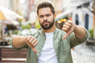 Hoşlanmamak. Üzgün sakallı genç adam işaret dilini gösteriyor, hoşnutsuzluğunu, memnuniyetsizliğini, kötü işini, hatasını ifade ediyor. Şehirdeki Sunshine Sokağı 'nda duran hoşnutsuz adam.