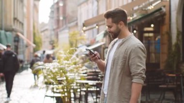 Gezgin sakallı, akıllı telefon kullanan, mesajlar yazan gezgin gezgin. Açık hava mobil navigatör uygulamasında haritada arama yapmak için bir yol arıyor. Şehirdeki Sunshine City Caddesi 'nin önünden geçen bir adam var.
