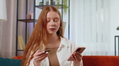 Kredi kartı ve akıllı telefon kullanan genç bir kız para transfer ederken, internetten nakitsiz alışveriş yapar, ev içinde yemek siparişi verir. Mutlu çocuk kanepede oturuyor