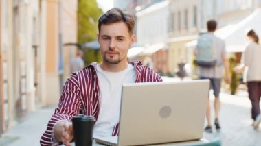 İnternet üzerinden eğitim alan bir adam. Sunny Street Cafe 'de dizüstü bilgisayarla uzak bir işte çalışıyor. Teneffüste dışarıda sohbet ediyor, kahve içiyor. Gülümseyen turist kameraya bakıyor.