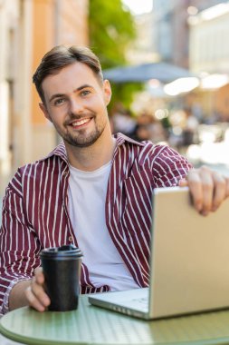 Yakışıklı adam, şehir merkezindeki kafeterya restoranının internet sitesinde açık bilgisayarla çalışmaya başlıyor. Tatilde açık havada sohbet ediyor. Genç turist kameraya bakıyor. Dikey