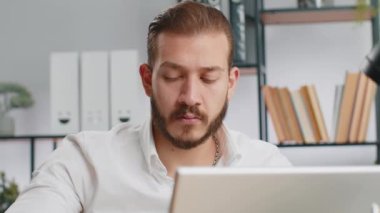 Yakın plan portre sakallı iş adamı ev işyerinde bilgisayarla çalışan serbest çalışan biri. Menajer serbest çalışan orta doğulu adam defter üzerinde çalışıyor mesajlar gönderiyor çevrimiçi alışverişler yapıyor