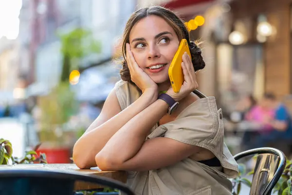 遠隔会話をする若い女性観光客の肖像は スマートフォンで話す 女の子の電話で予期せぬ良いニュースゴシップ市内のカフェテリアでテーブルに座って話している アウトドアライフスタイル — ストック写真