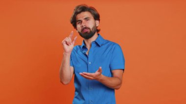 Biraz daha lazım, lütfen yardım et. Küçük boyutlarda, en ufak bir işaret gösteren, kuşkucu bir gülümsemeyle küçük bir jest yapan bir adam. Orta Doğulu adam turuncu stüdyo arka planında tek başına.