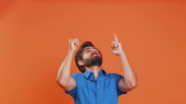 親指を示し 頭の上の空の場所を指す若者 商業テキストのための広告区域 商品の昇進の広告のためのコピーのスペース オレンジ色のスタジオで孤立した男 ライフスタイル — ストック動画