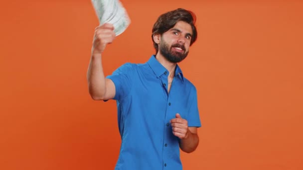 有钱的老板很高兴年轻人挥动钞票 像扇子一样的钞票 成功的商业生涯 彩票中奖者 大收入 中东人在橙色背景下被隔离在室内 — 图库视频影像