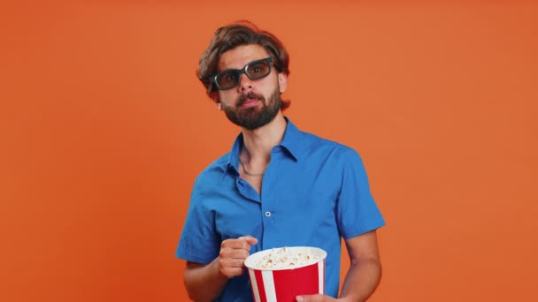 兴奋的年轻人戴着3D眼镜吃爆米花 看有趣的电视连续剧 体育游戏 在线社交媒体电影内容 穿着衬衫的中东人被隔离在橙色工作室的背景下 — 图库视频影像
