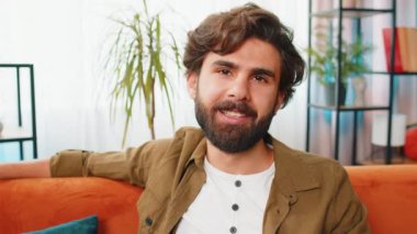 Mutlu, sakin, orta doğulu bir adamın portresi kanepede gülümseyen dostane bir gülümseme, mutlu bir yüz ifadesi başka tarafa bakıyor, dinleniyor, rahatlıyor, iyi haberler veriyor, zaferi kutluyor. Oturma odasındaki Arap adam.