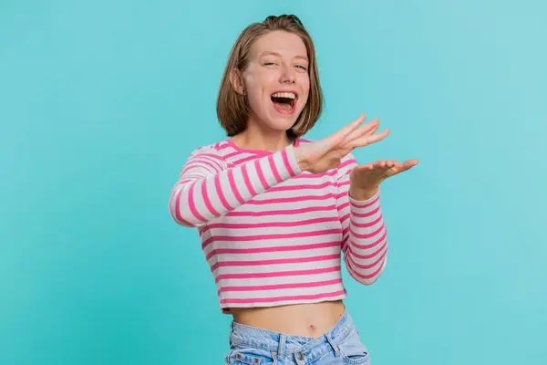 Young woman showing wasting, throwing money around, more tips, big profit, winning lottery jackpot, successful shopping payment purchase, cashback. Girl in crop top isolated on blue studio background