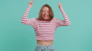 Neşeli bir kadın bağırıyor, el kol hareketi yapıyor başarıyı kutluyorum, doğum gününü kazanıyorum, piyango vuruşu hedefliyorum, iyi haberlerim var. Mavi atölyenin arka planında, ekili bluzlu genç kız.
