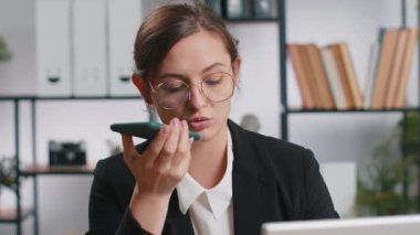 Kafkasyalı iş kadını çalışıyor. Ofis masasında dizüstü bilgisayarla cep telefonu hoparlörü konuşuyor. Menajer serbest çalışan mutlu kız kurye sohbet uygulamaları kullanarak akıllı telefon tutuyor. İstihdam, meslek