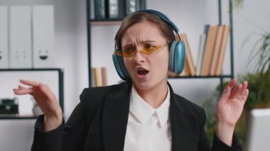 Happy, ofisteki dizüstü bilgisayarda çalışan, kulaklık takan ve favori disko müziği ve dans dinleyen neşeli beyaz iş kadını. Serbest çalışan kız dinleniyor, mola veriyor.