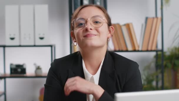 在家里写字楼的写字台上 一个快乐的 面带微笑的黑发白人女商人的画像 转过头看着相机 身着正式服装的女性 漂亮女孩远程上网工作在笔记本电脑上 — 图库视频影像