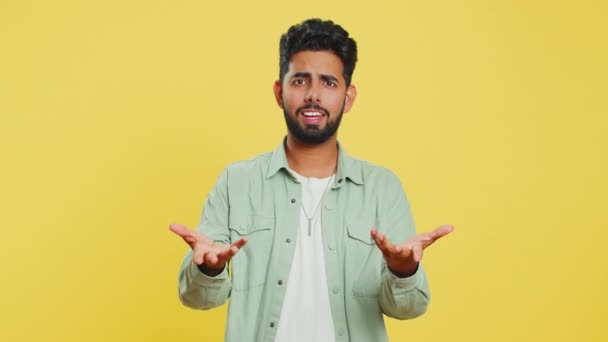 どうしたの どうして 怒っているインディアン男性は憤慨した表情で手を挙げ 失敗の理由を尋ね トラブルによる不信感の刺激を示しました イエロースタジオで孤立したアラビアの若い男 — ストック動画