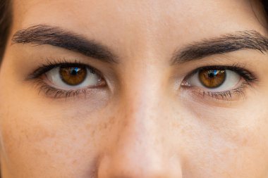 Extreme close-up macro portrait of smiling young adult Caucasian woman face. Brunette girl eyes, looking at camera. Dark brown eyes of lady. Portrait of positive female opening wide her closed eyes clipart