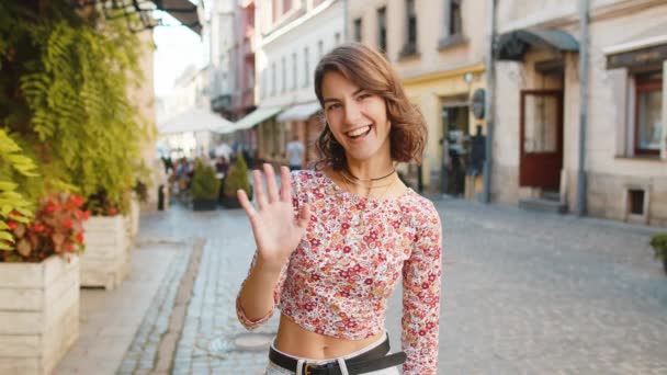 Halo Wanita Muda Tersenyum Ramah Pada Kamera Melambaikan Tangan Isyarat — Stok Video