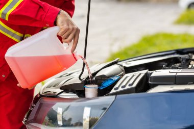 Kapalı devre servis elemanı şoförü ön cam temizleme sıvısını teneke kutudan kaput araba deposuna boşaltıyor. Yaz ya da kış sıvısı ön cam temizleyicisi