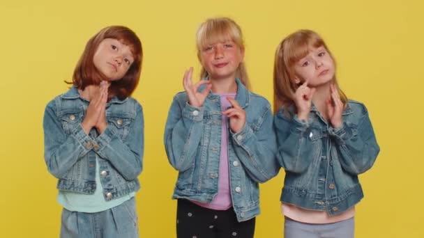 頼む助けてくれ 10代の少女たちは祈り 願い事をし 希望に満ちた表情で祈り 許しを請う 妹たちよ 黄色の背景に隔離された3人の兄弟 — ストック動画