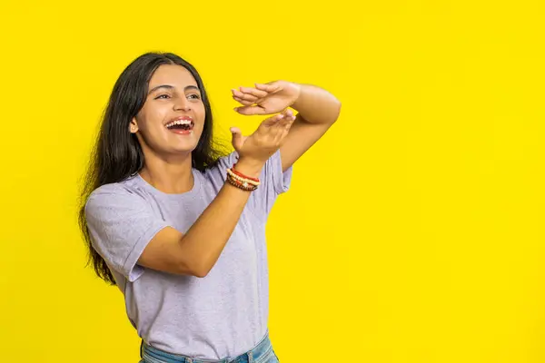 Indian woman showing wasting throwing sharing money around more tips big profit winning lottery jackpot, successful shopping payment purchase cashback. Arabian Hindu girl isolated on yellow background