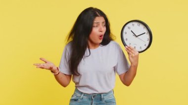 Anksiyetesi olan Hintli genç bir kadın, saati kontrol ediyor, işe geç kalıyor, gecikiyor, son teslim tarihi. Sarı arka planda dakikalarca izole edilmekten korkan Arap bir kız.
