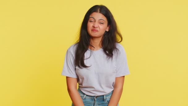 遊び心のあるインドの若い女性は カメラで顔を作る舌を示し 冗談を言って 馬鹿げた顔で応える いじめ いじめ 陽気で面白いアラビアの少女は黄色の背景で孤立しました — ストック動画