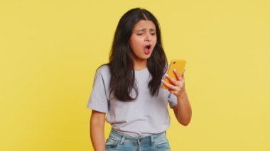 Üzgün Hintli kadın akıllı telefon daktilo kullanıyor, oyun oynuyor, kaybediyor, piyango aniden şaşırıyor kötü şans kaybı şanssız haber. Sarı arka planda izole edilmiş Arap Hindu kız