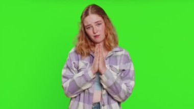 Lütfen, Tanrım yardım et. Kafkasyalı bir kadın kameraya bakıp dilek diliyor, umutlu bir şekilde yalvarıyor, özür diliyor, meditasyon yapıyor. Kızıl saçlı kız yeşil krom anahtar arka planında izole edilmiş.