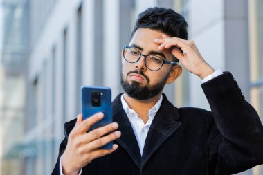 Hintli işadamı akıllı telefon daktilo kullanıyor, kaybediyor, kötü haber, servet kaybı, iflasın eşiğinde. Şehir merkezindeki Hindu serbest çalışan Arap bir adam. İş adamı yaşam tarzı