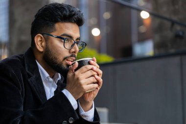 Mutlu sakallı Hintli işadamı sabah kahvesini içiyor ve dışarıda gülümsüyor. Dinleniyorum, ara veriyorum. Şehir merkezindeki caddeye gitmek için kahve içen Hintli bağımsız Arap bir adam. Yaşam biçimi