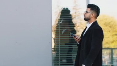 Hintli işadamının e-posta yazarak mesajları cevaplarken görüntüsü mobil ekran uygulaması gibi. Şehir merkezinde yürüyen Arap Hindu serbest çalışan adam. İş adamları