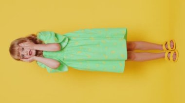 Korkmuş, sarışın kız çocuğu tehlike sorunlarından korkuyor, fobisi var, anksiyete bozukluğu var, korku, güvensizlik, stres, panik gösteriyor. Sarı arka planda küçük çocuklar. Dikey