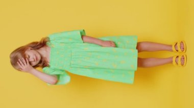 Avuç içi. Yazıklar olsun sana. Üzgün, sarışın kız çocuğu avuç içi hareketi yapıyor. Sıkılmış, hayal kırıklığına uğramış, kötü haber. Sarı arka planda izole edilmiş küçük çocuklar. Dikey