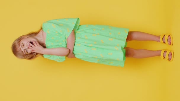疲れたブロンドの子供の少女は 勉強教育後に睡眠不足に苦しむ不注意な気分で眠っている不注意な感じ 黄色の背景に孤立した19人の子供たち バーティカル — ストック動画