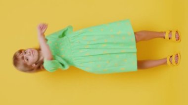 Saldırgan kızgın genç kız kameraya karşı dövüşmeye çalışıyor, yumruklarını sallıyor, ifadeyle boks yapıyor, cezalandırıyor, taciz ediyor, öfkeleniyor. Stüdyonun sarı arka planında izole edilmiş kabadayı çocuk. Dikey