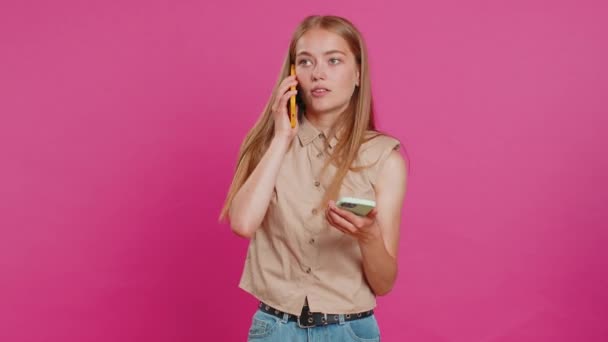 イライラした神経症は 2台の携帯電話で話す若い女性が会話の紛争の争いの論争で問題を議論することを強調しました ピンクのスタジオの背景に孤立した少女 — ストック動画