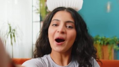 Hintli genç kadın blogcu internet üzerinden akıllı telefondan selfie çekerken sosyal medya abonelikleriyle internet üzerinden video görüşmesi yaparken POV görüşü. Mutlu Arap kızı cep telefonunu elinde tutuyor.