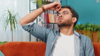 Hasta Hintli adam baş ağrısı problemini tedavi etmek için tapınakları ovuyor, tansiyon, migren, stres, ekşitme, evde yüksek tansiyon. Arap Hintli adam, kanepede kapalı bir odada.