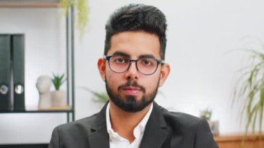 Ofis masasındaki mutlu, sakallı Hintli işadamının portresi yüzünü kameraya çevir. Resmi takım elbiseli erkek Hindu. Yakışıklı girişimci uzaktan kumandalı internetten çalışıyor.