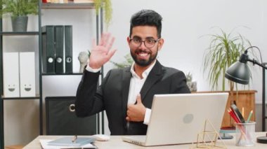 Hoş geldiniz. Bilgisayarda çalışan Hintli iş adamı kameraya gülümseyen ve el sallayan el sallayan merhaba, selamlaşma ya da güle güle, iş yerindeki çalışma masasında misafirperver bir ifadeyle karşılama.