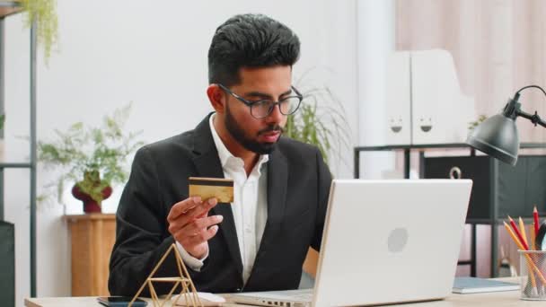 阿拉伯商人程序员软件开发人员使用信用卡进行网上购物 并使用笔记本电脑在总部写字台上 印度自由职业者商人 — 图库视频影像